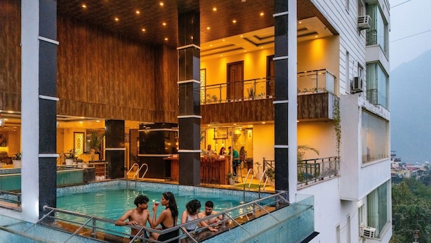 A rooftop swimming pool with a bar area and a view of the city. - Moustache Rishikesh Luxuria (Narendranagar)