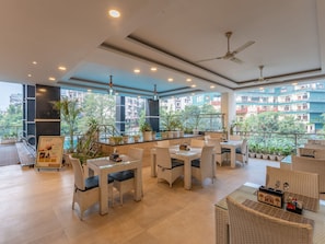 A spacious outdoor seating area with wicker furniture, potted plants, and a view of the cityscape. - Moustache Rishikesh Luxuria (Narendranagar)