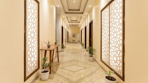 A hallway with a marble floor, potted plants, and decorative screens. - Moustache Rishikesh Luxuria (Narendranagar)