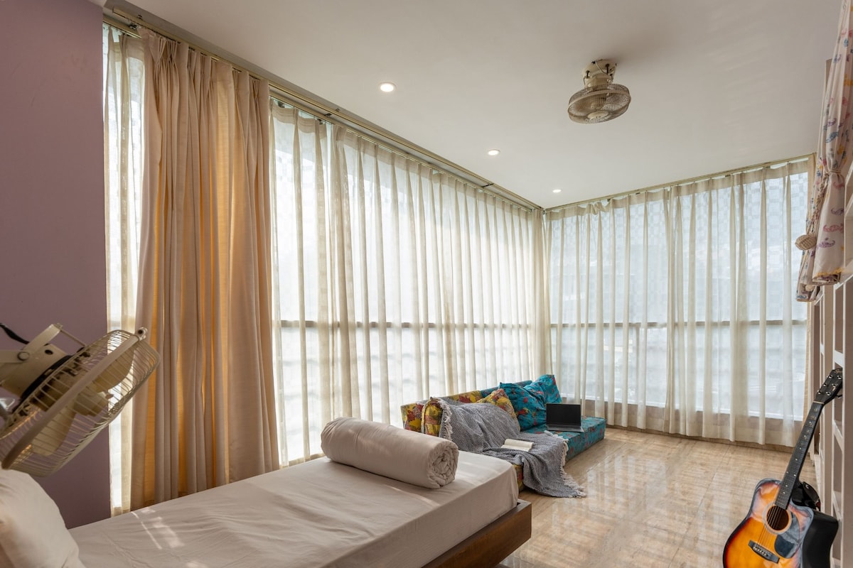 A bedroom with a bed, a guitar, and a couch.
