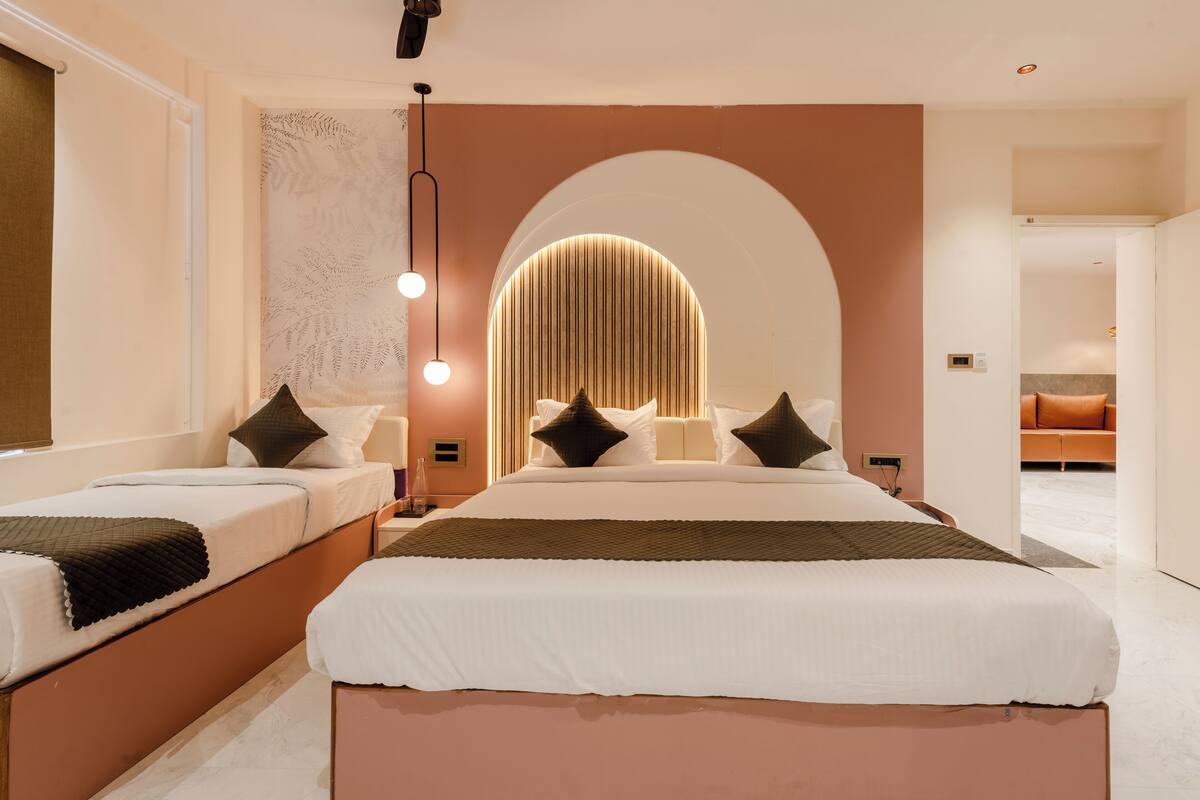 Una habitación de hotel moderna con dos camas, un amplio ventanal en arco y un diseño de pared original.