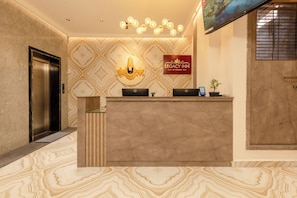 A reception desk with a marble floor, a wall-mounted sign for Legacy Inn, and an elevator to the left. - Legacy Inn, Mysore (Mysore)