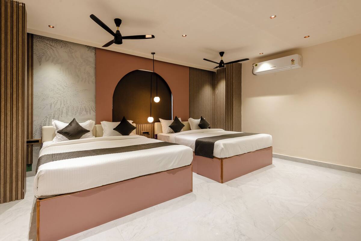 Una habitación de hotel moderna con dos camas, un ventilador de techo, un equipo de aire acondicionado y un panel decorativo en la pared.