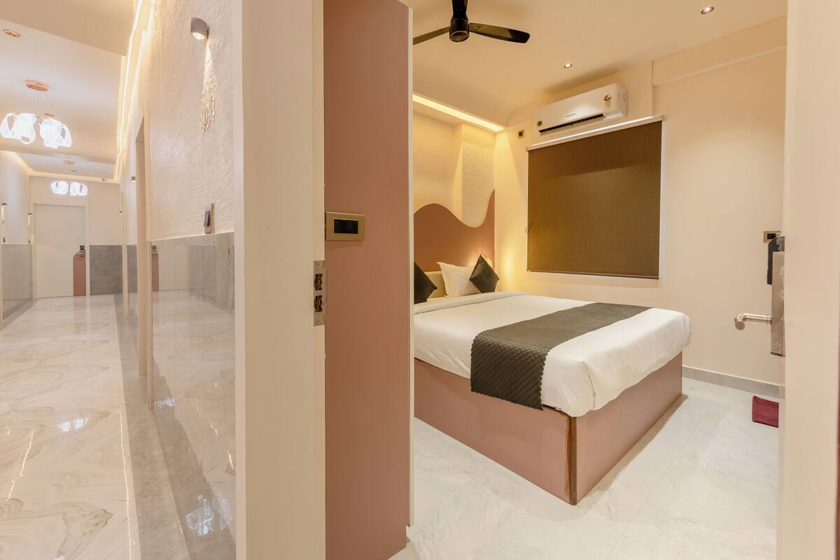 Una habitación de hotel moderna con una cama grande, ventilador de techo y aire acondicionado instalado.