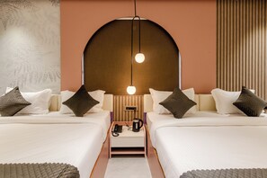 Quarto de hotel moderno com duas camas, uma mesa de cabeceira, uma cafeteira e uma luminária fixada na parede.
