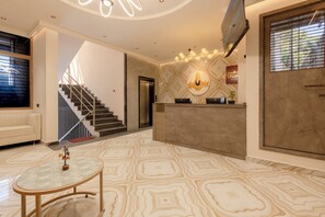 A modern hotel lobby with a staircase, a reception desk, and a patterned floor. - Legacy Inn, Mysore (Mysore)