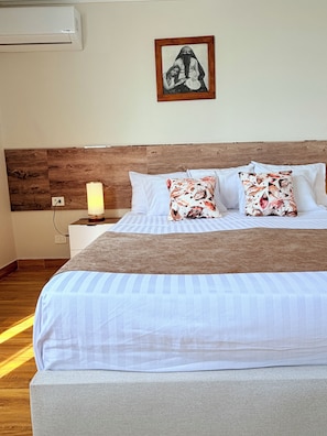Een netjes opgemaakt bed met een houten hoofdeinde, witte kussens en een plaid met bloemenprint.