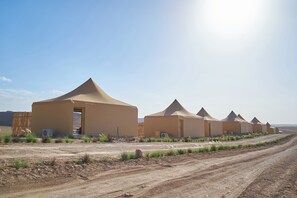 A row of desert tents with a dirt road in front, each with a small garden area. - Stellar Desert Camp (Marrakech)