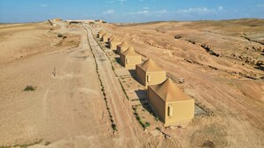 A row of desert-style buildings with a dirt road leading to them. - Stellar Desert Camp (Marrakech)