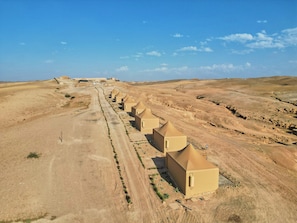 Una hilera de edificios de estilo desértico con un camino de tierra que los conduce.