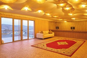 A spacious room with a large window, a red carpet, and a white sofa. - Stellar Desert Camp (Marrakech)
