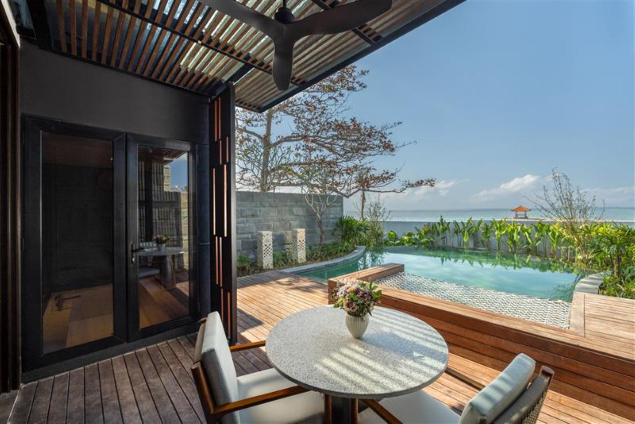 Un espacio exterior moderno con piscina, terraza de madera y asientos.
