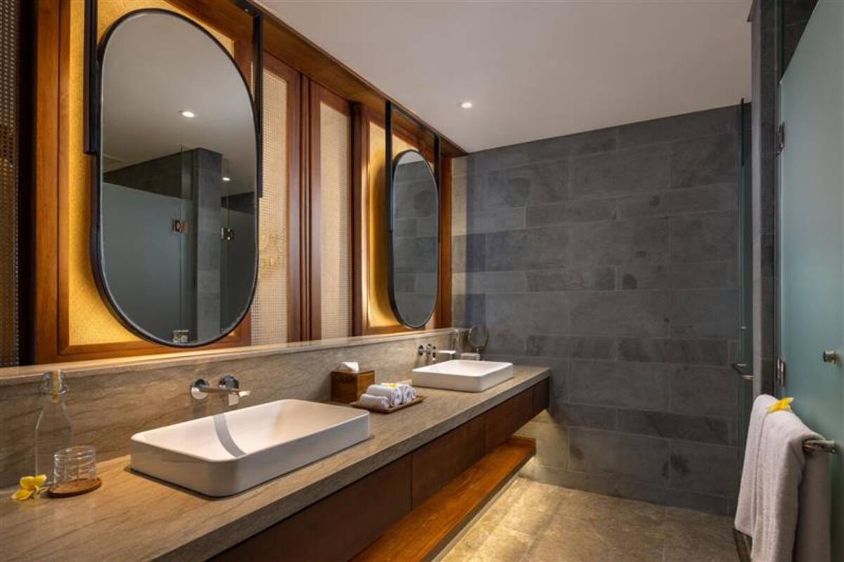 Une salle de bain moderne avec deux lavabos, de grands miroirs et un espace douche.