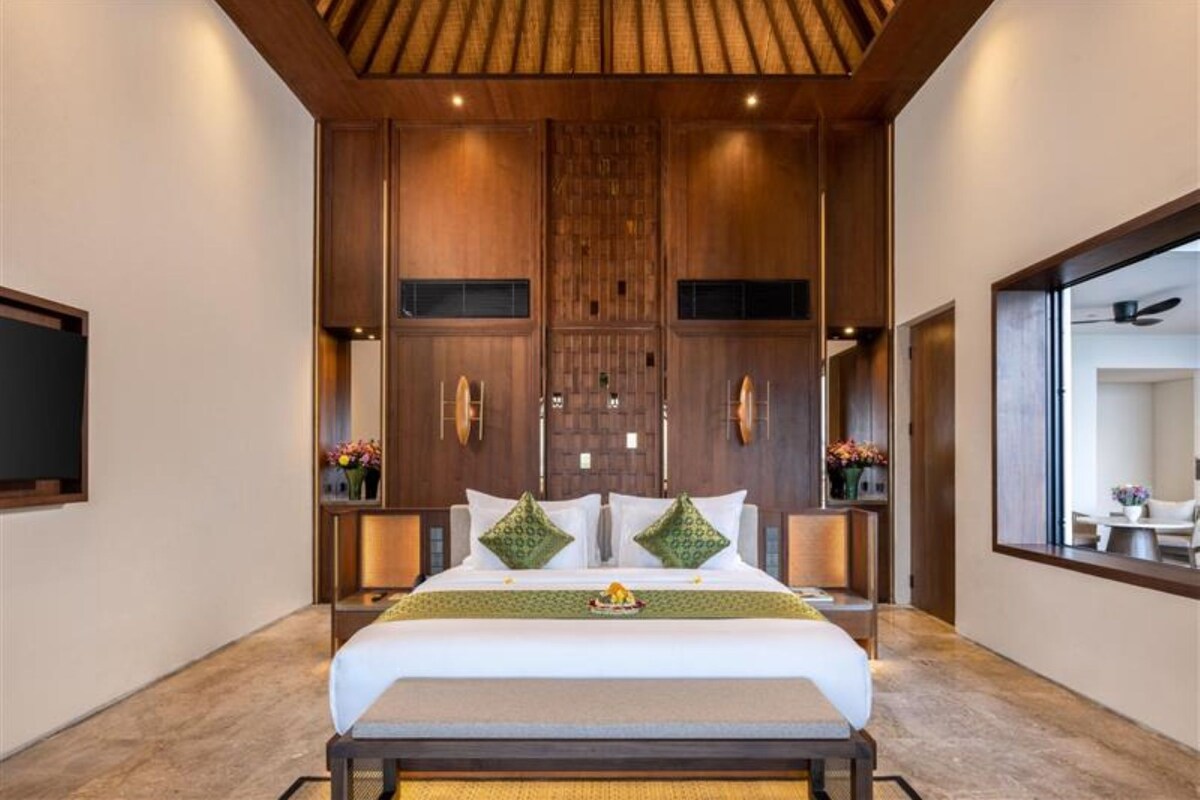 Een moderne hotelkamer met een groot bed, houten paneelwanden en een grote spiegel aan de muur.