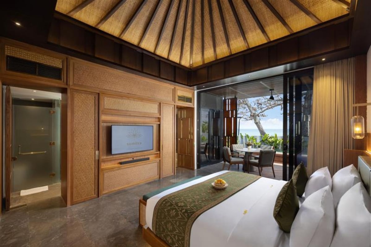Une chambre d’hôtel moderne dotée d’un grand lit, d’une télévision et d’un balcon offrant une vue sur l’océan.