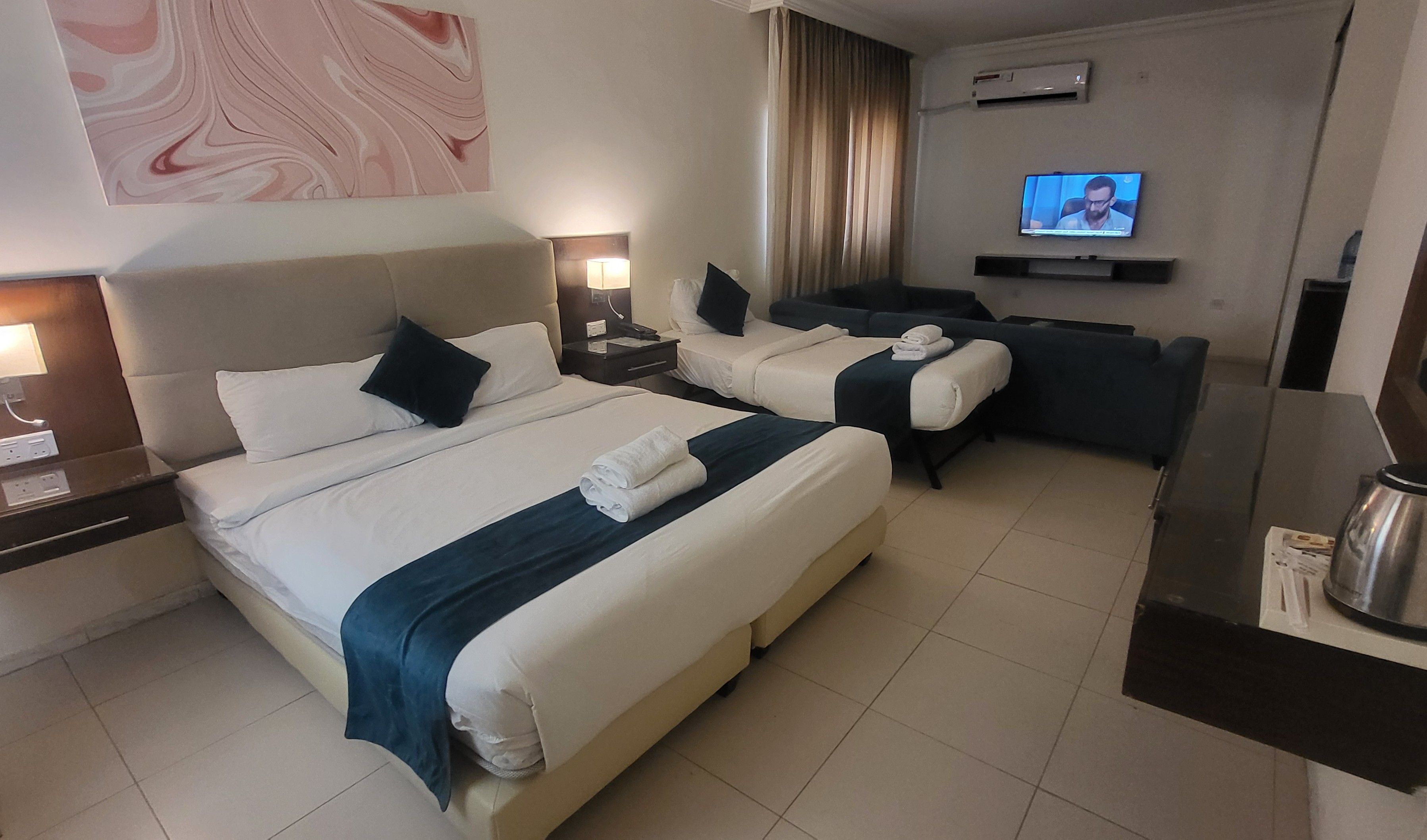 Habitación de hotel con dos camas, un sofá, un televisor y una cafetera.