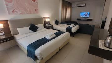 Habitación de hotel con dos camas, un sofá, un televisor y una cafetera.