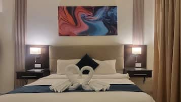 Una habitación de hotel con una cama grande, dos mesitas de noche, un cabecero y un cuadro abstracto colgado en la pared.