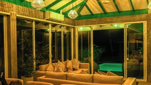 Et hyggeligt opholdsområde indendørs med en sofa, et bord og en glasindrammet terrasse.