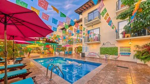 An indoor pool area with lounge chairs, a swimming pool, and colorful flags. - Casa Maria Hotel Vallarta (Puerto Vallarta)