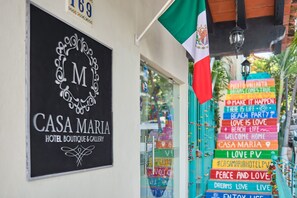 A sign for 'CASA MARIA HOTEL BOUTIQUE & GALLERY' with a decorative emblem and a street sign with various phrases. - Casa Maria Hotel Vallarta (Puerto Vallarta)