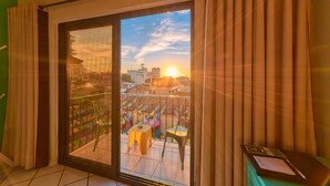 A room with a sliding glass door leading to a balcony with a city view and a table with chairs. - Casa Maria Hotel Vallarta (Puerto Vallarta)