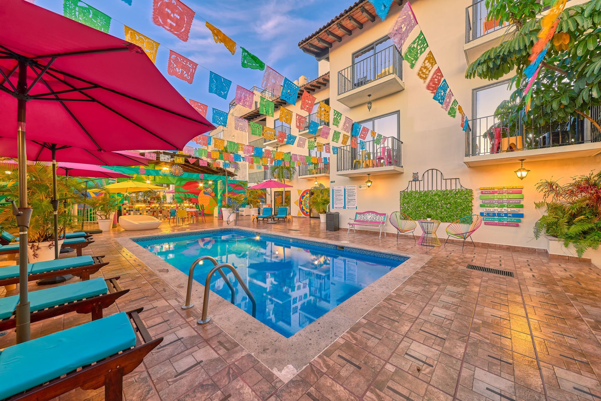An indoor pool area with lounge chairs, a swimming pool, and colorful flags.