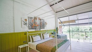 A four-poster bed with a green and white color scheme, a small bedside table, and artwork on the wall. - Amba Yaalu - Thema Collection (Kandalama)