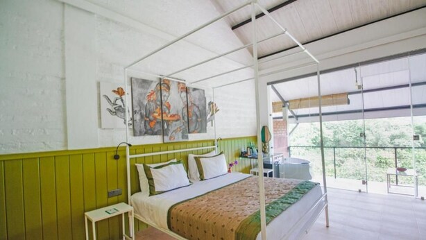 A four-poster bed with a green and white color scheme, a small bedside table, and artwork on the wall. - Amba Yaalu - Thema Collection (Kandalama)