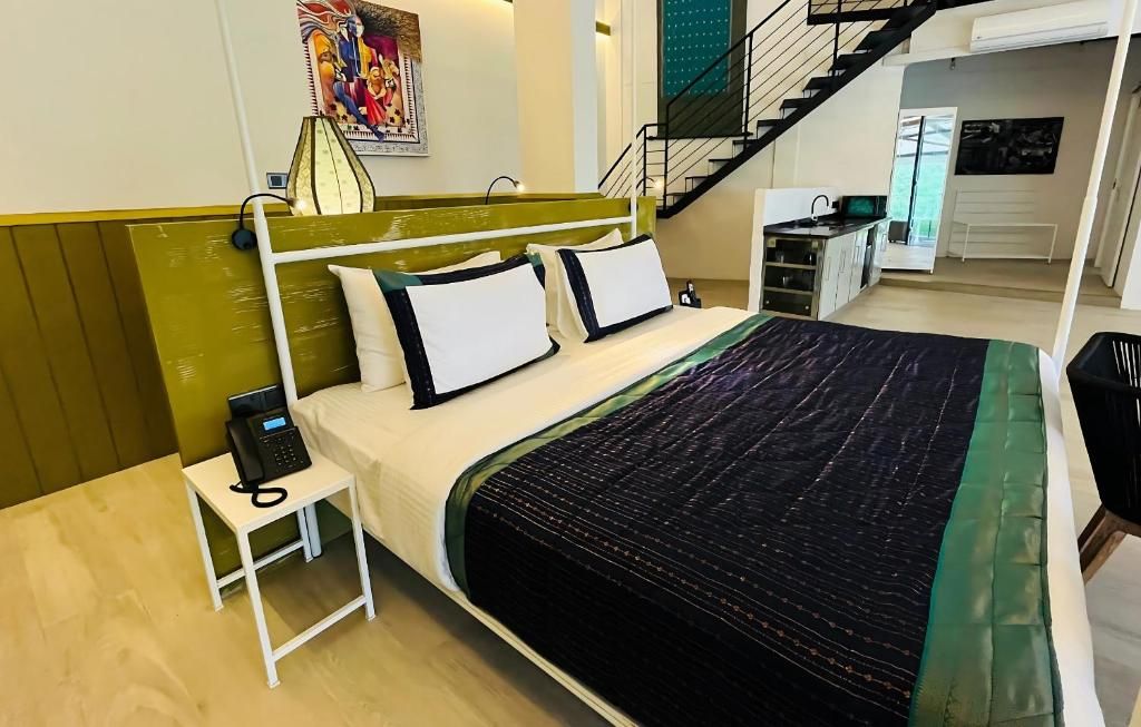 Habitación de hotel con cama, teléfono junto a la cama y vista a la cocina y la escalera.