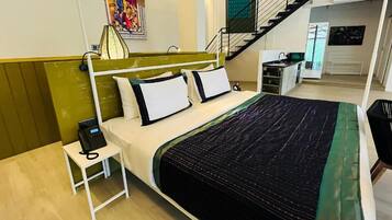 Habitación de hotel con cama, teléfono junto a la cama y vista a la cocina y la escalera.