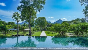 A swimming pool with a clear view of a pathway leading to a mountain. - Amba Yaalu - Thema Collection (Kandalama)