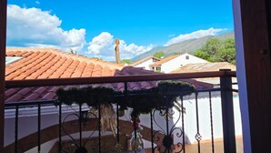 Un balcone con vista su edifici dalle tegole rosse, cielo sereno e una montagna all'orizzonte.