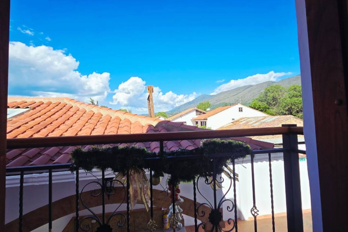 Un balcó amb vista a edificis de teules vermelles, un cel serè i una muntanya a la distància.