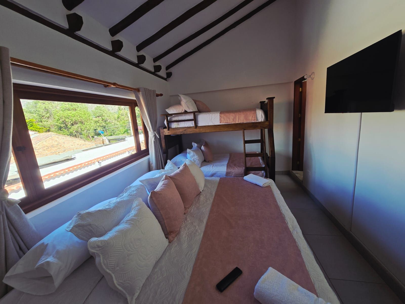 A bedroom with a bunk bed, a large window, and a flat-screen TV.