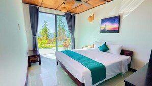 A hotel room with a bed, a desk, a chair, a ceiling fan, and a view of the outdoors. - Adora Bay Ke Ga Beach Resort (Tan Thanh)