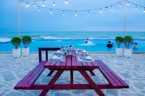 A beachside dining area with a table set for two, overlooking the ocean. - Adora Bay Ke Ga Beach Resort (Tan Thanh)
