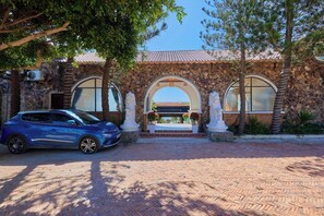 A building with a stone facade, arched entrance, and a blue car parked in front. - Adora Bay Ke Ga Beach Resort (Tan Thanh)