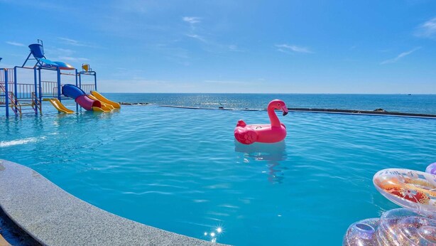 A swimming pool with a slide and a pink flamingo float. - Adora Bay Ke Ga Beach Resort (Tan Thanh)