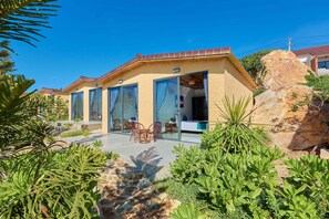 A modern house with a patio, glass doors, and a garden with various plants. - Adora Bay Ke Ga Beach Resort (Tan Thanh)