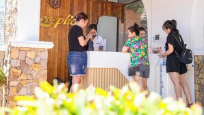 A reception area with a wooden wall, a clock, and a stone wall. - Adora Bay Ke Ga Beach Resort (Tan Thanh)