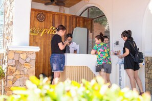 A reception area with a wooden wall, a clock, and a stone wall. - Adora Bay Ke Ga Beach Resort (Tan Thanh)