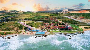 An aerial view of a coastal resort with a swimming pool, beach, and ocean waves. - Adora Bay Ke Ga Beach Resort (Tan Thanh)