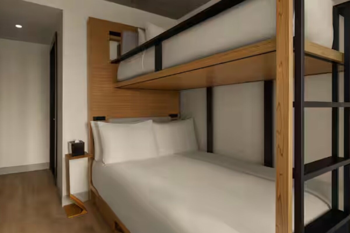 Dormitorio con literas, cabecera de madera, mesita de noche y espejo.