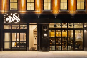 Un hotel con un llamativo letrero que dice 'Hotel 35S', un amplio acceso de vidrio y asientos interiores visibles a través de las puertas.