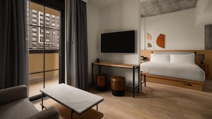A modern hotel room with a bed, a TV, a desk, a chair, and a view of a building through a large window. - Hotel 38 New York City, Tapestry Collection by Hilton (New York)