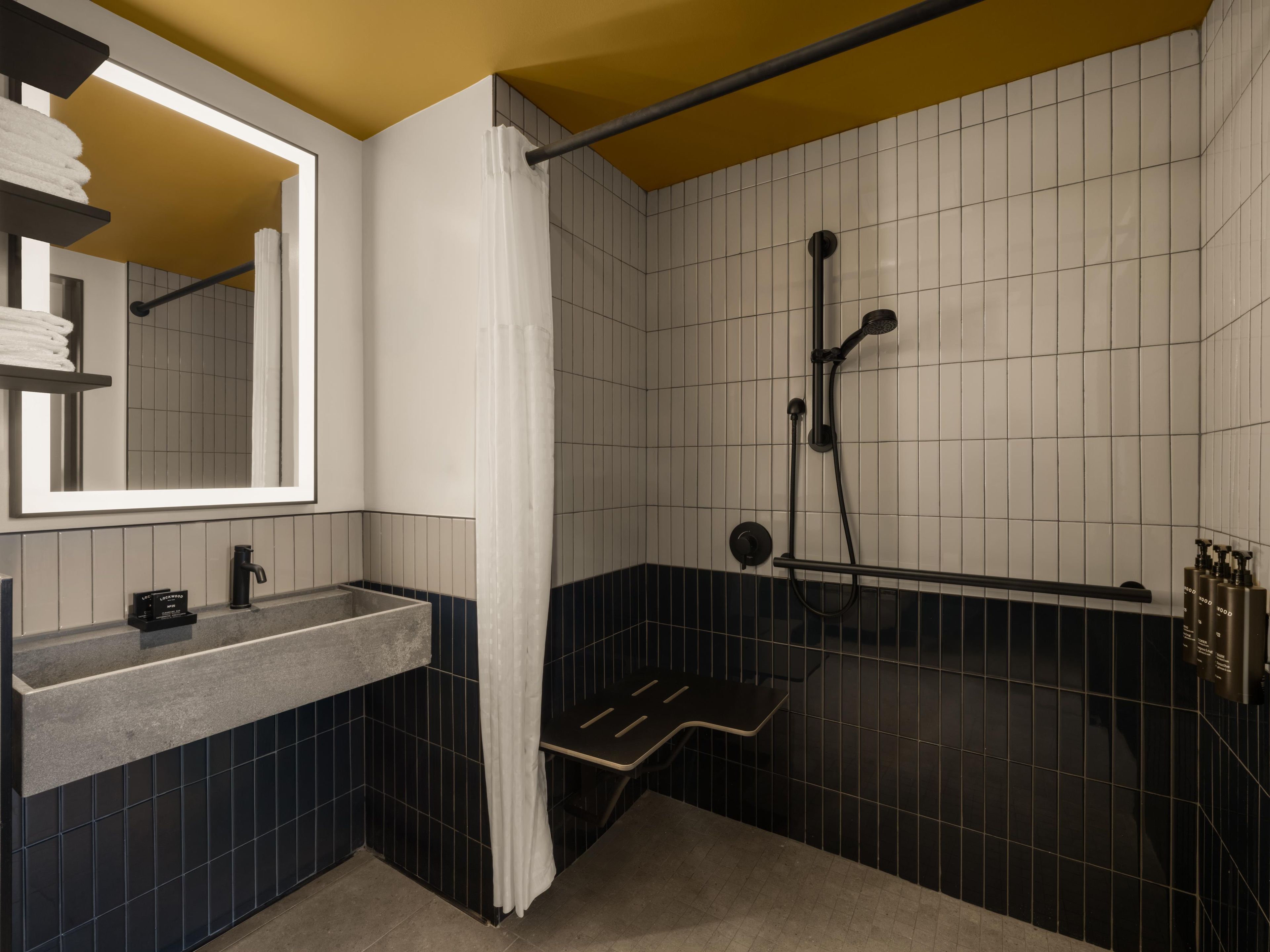A modern bathroom with a large mirror, a sink, a shower, and a towel rack.