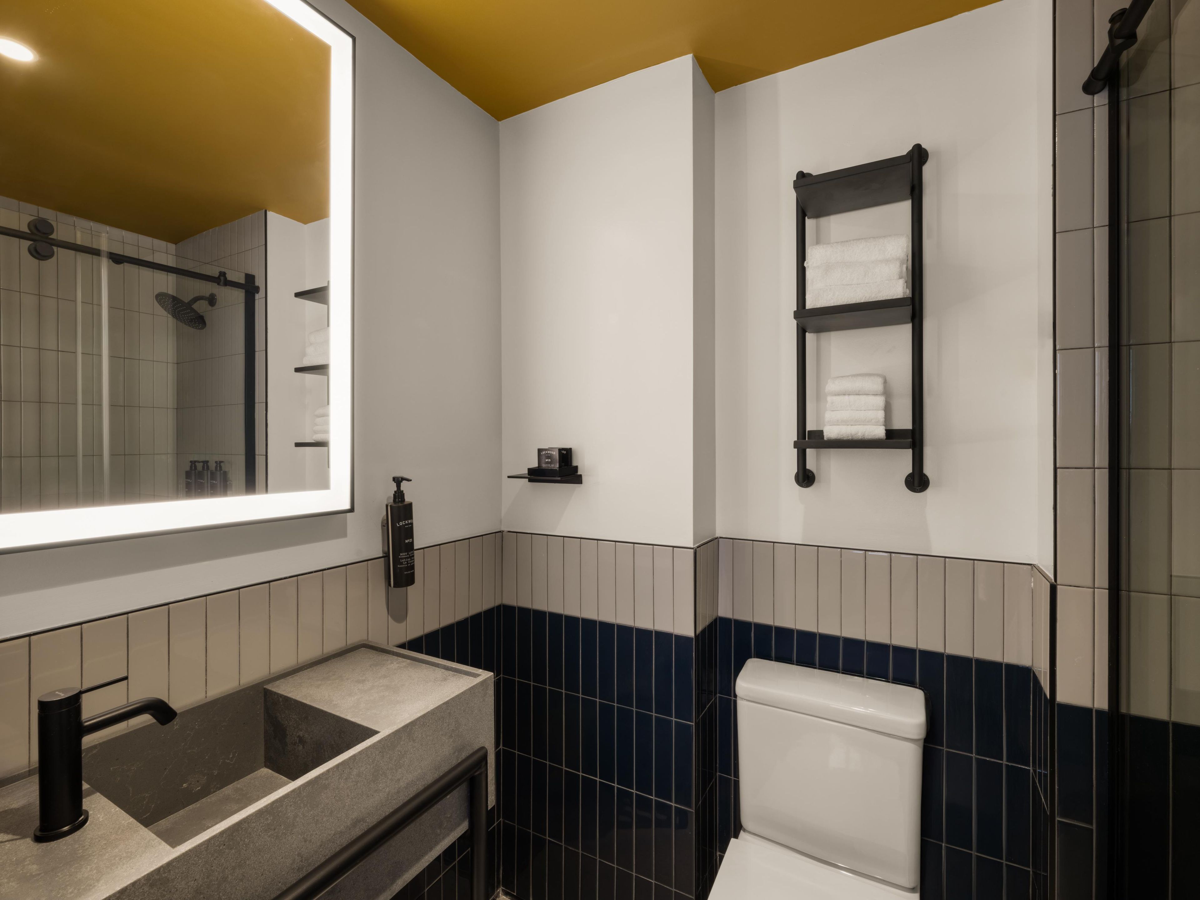 A modern bathroom with a large mirror, a sink, a toilet, and a towel rack.