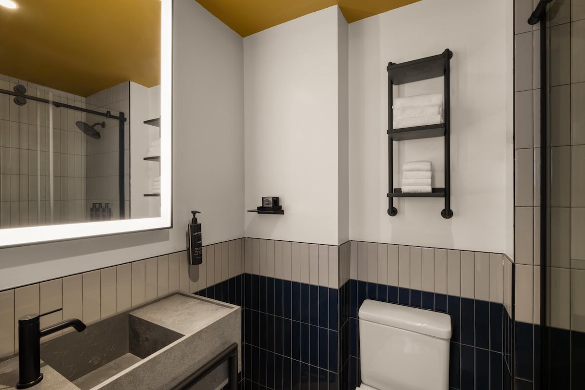 Un baño moderno con un espejo grande, un lavabo, un inodoro y un perchero para toallas.