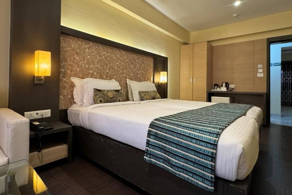 A modern hotel room with a large bed, bedside tables, a desk, and a wardrobe.